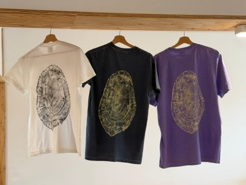 Takumi tree-ring T-shirts in white, denim navy and violet, showing the back prints